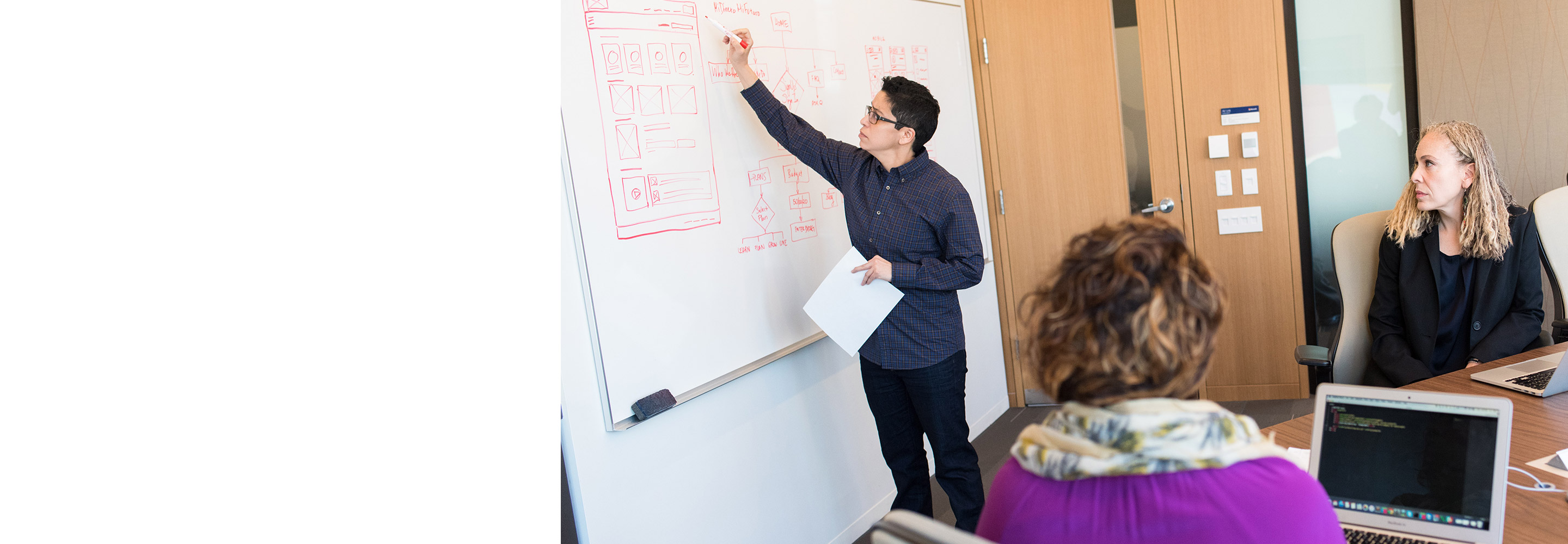 Two woman watching man on whiteboard