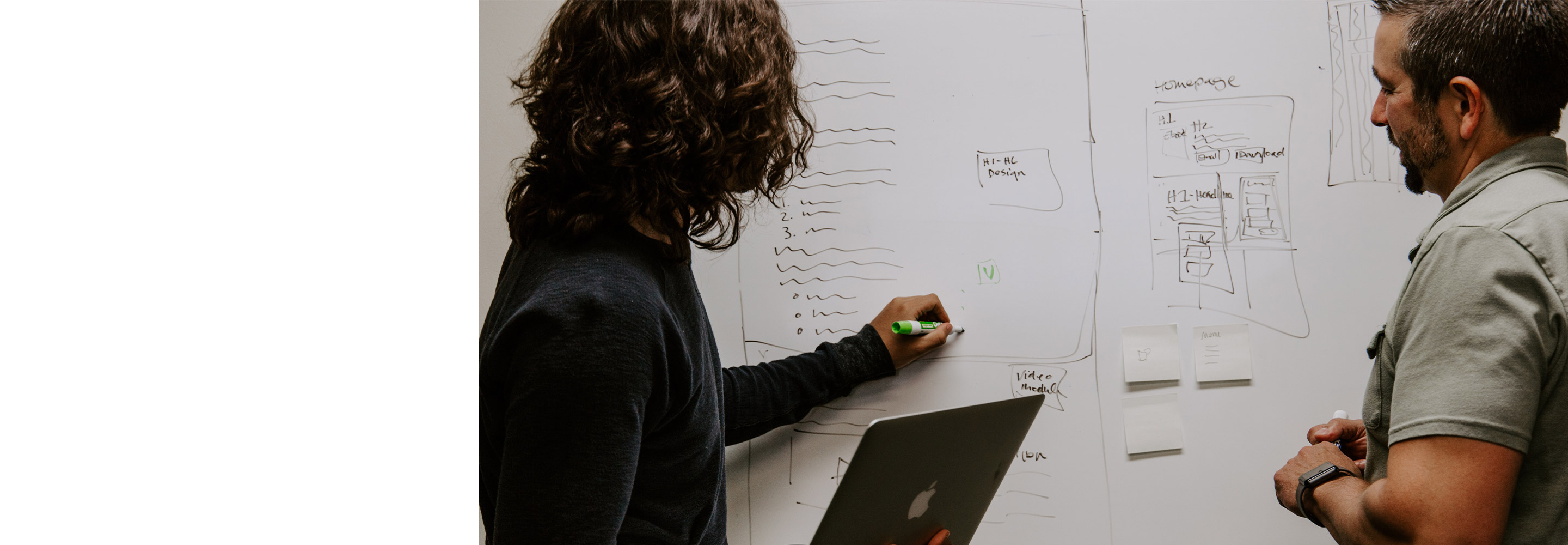 Two men take notes on a whiteboard 